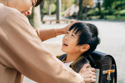 A woman assists a young boy as he adjusts his backpack, showcasing a moment of care and support.