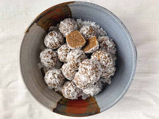 A bowl filled with coconut shaved chai bliss balls showcasing a variety of textures and ingredients.