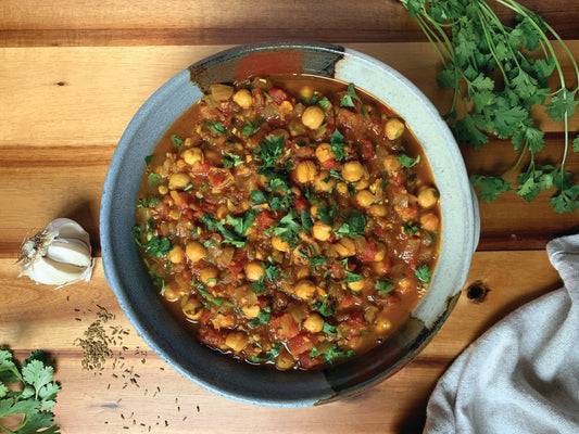 A vibrant chickpea masala garnished with fresh garlic and cilantro, served in a bowl, showcasing its rich colors and textures.
