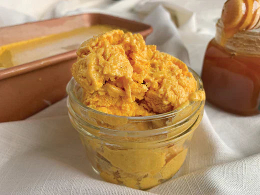 A jar of mango ice cream beside a spoon and a bowl filled with golden honey, showcasing a delightful spread. a healthy dish.