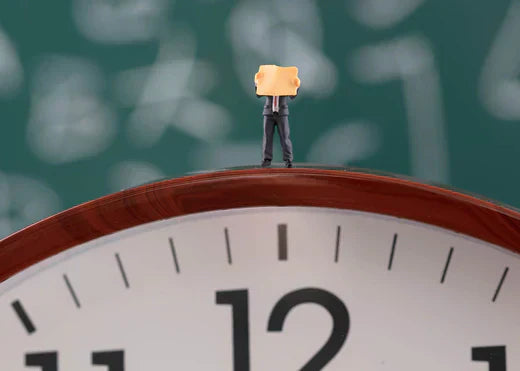 A man stands atop a large clock, holding a newspaper, creating a whimsical scene of time and curiosity.