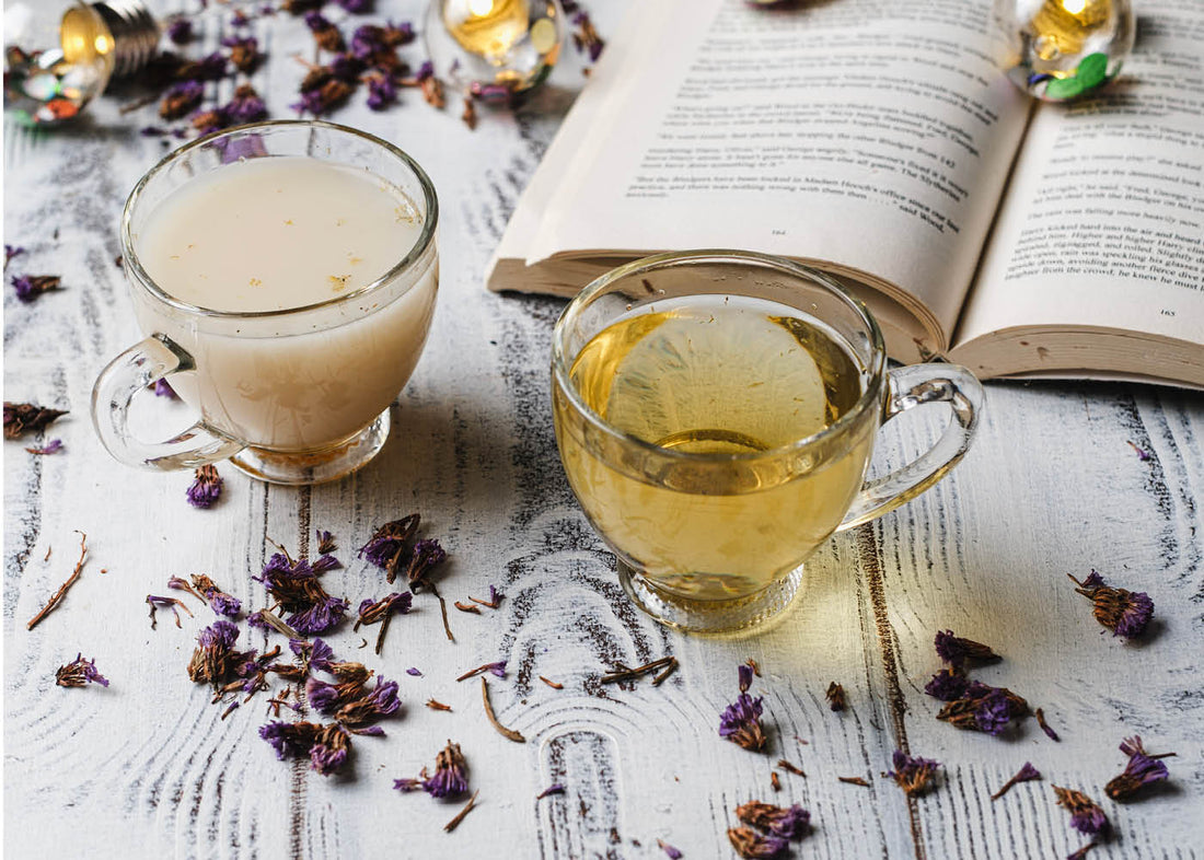 A cup of dreamy bee brew tea beside an open book resting on a rustic wooden table, creating a cozy reading atmosphere.