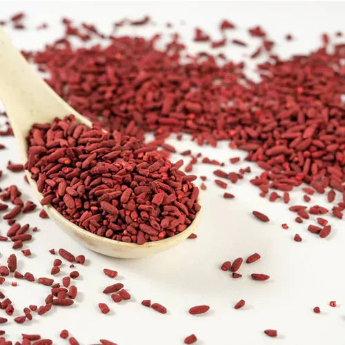 A collection of red yeast rice scattered across a clean white surface, showcasing their vibrant color and natural shape.