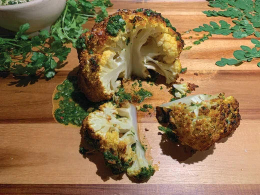A halved cauliflower showcasing its white florets and green leaves, highlighting its fresh and healthy appearance.