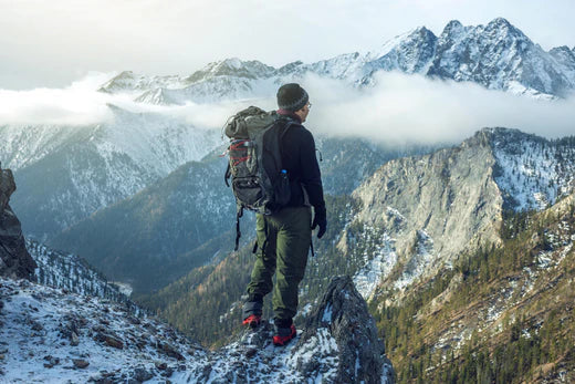 man with a backpack standing at the top of a snowy mountain beautiful view