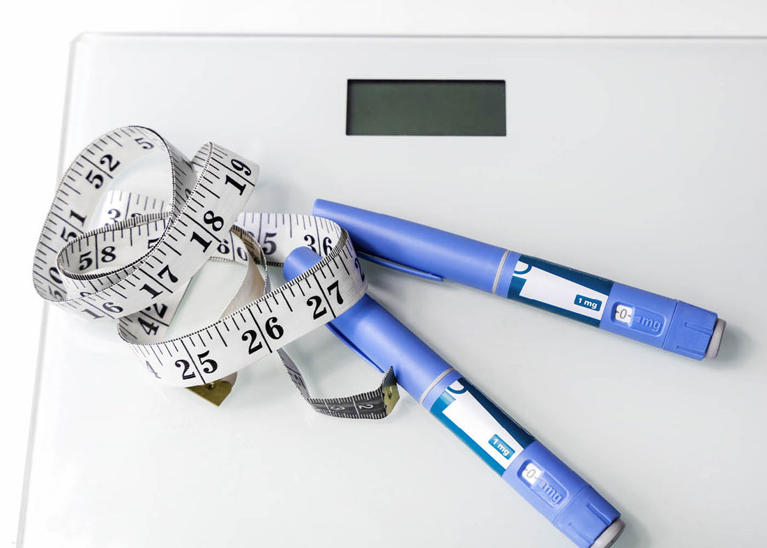 Digital scale with measuring tape and two ozempic insulin pens, representing weight management and diabetic care tools in the context of natural GLP-1 promoters for weight loss.