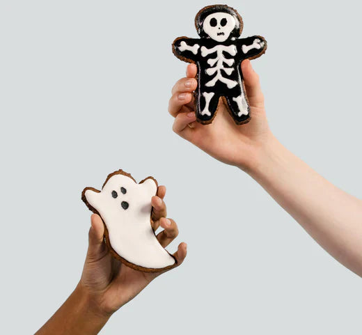 Two hands delicately hold cookies adorned with festive Halloween decorations, showcasing a delightful seasonal treat.